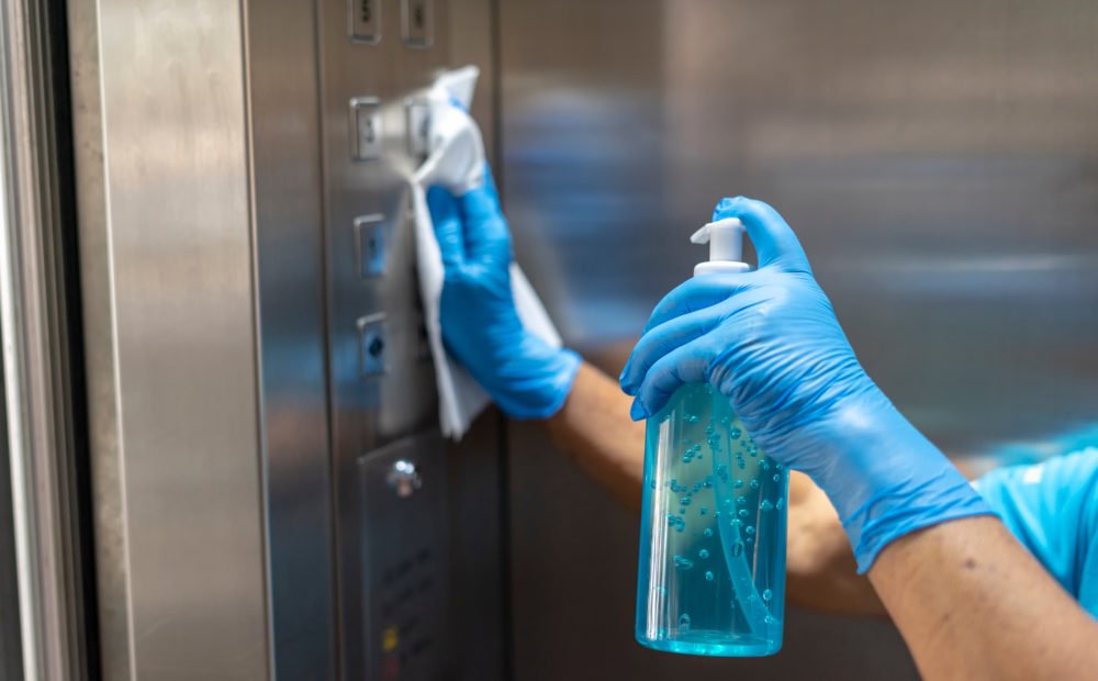Property Manager disinfecting elevator for COVID